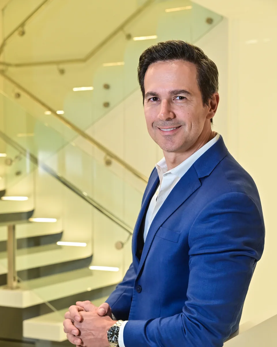 Dr. Andre Campana sorrindo, na escada da clínica em Vitória-ES